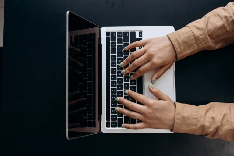 Top view of hands typing on a laptop keyboard, showcasing modern technology use.